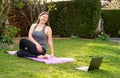 Happy smiling woman practicing pilates lesson online in garden doing stretching  outdoors Royalty Free Stock Photo