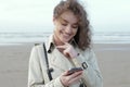 Happy smiling woman reading good news on her mobile phone standing on a beach Royalty Free Stock Photo