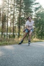 Happy, smiling woman is roller skating, at high speed, on the road, on a summer day. Active holidays. Royalty Free Stock Photo