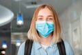 Happy smiling woman Schoolgirl in blue protective mask with backpack. Young woman student in medical mask. Portrait of blonde