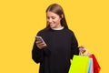 Happy smiling woman with shopping bags is looking at her phone. Royalty Free Stock Photo