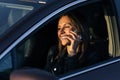 Happy smiling woman speaking on the phone while driving a car on a sunny day. Received good news Royalty Free Stock Photo