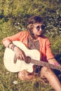 happy smiling woman in sunglasses sits on the grass with a guitar. summer vacation concept. Royalty Free Stock Photo