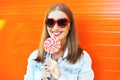 Happy smiling woman in sunglasses with sweet lollipop over colorful orange backgroun Royalty Free Stock Photo