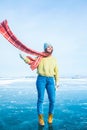 Happy smiling woman traveler in trendy winter hat and scarf looking away while standing outdoors on frozen lake Royalty Free Stock Photo