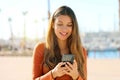 Happy smiling woman using mobile phone walking in port city street Royalty Free Stock Photo