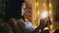 Happy smiling woman using tablet computer for sharing social media lying in bed at home at night Royalty Free Stock Photo