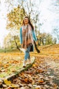 Happy smiling woman wearing brown boots and jeans in autumn yellow foliage walking in park or forest Royalty Free Stock Photo