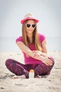 Happy woman in straw hat and sunglasses using sun lotion, concept of sun protection on beach Royalty Free Stock Photo