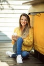 Happy smiling woman is wearing yellow sweater drinking coffee latte near old retro bus Royalty Free Stock Photo