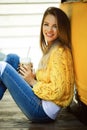 Happy smiling woman is wearing yellow sweater drinking coffee latte near old retro bus Royalty Free Stock Photo