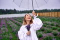 Happy smiling woman in white costume dancing under rain, holding umbrella and bouquet and smiling in overcast. shallow depth of Royalty Free Stock Photo