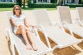 Happy smiling woman in white dress sitting on deck chair Royalty Free Stock Photo