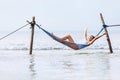 Happy smiling woman in white swimsuit lies in hammock swing over