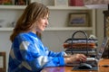 Happy smiling woman working on a laptop computer at home Royalty Free Stock Photo