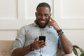 Happy smiling young african american guy holding cell phone. Royalty Free Stock Photo