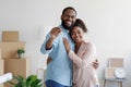 Happy smiling young african american loving family hugging in new home among boxes and showing house keys Royalty Free Stock Photo