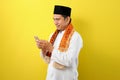 Happy Smiling Young Asian Muslim man wearing moslim clothes holding mobile phone look at phone screen Royalty Free Stock Photo