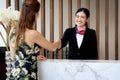 Happy smiling young beautiful Asian female receptionist in black suit shaking hands greeting customer woman guest at hotel Royalty Free Stock Photo