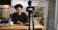 Happy smiling young beautiful black vlogger woman filming new video using professional camera at home table slow motion. Royalty Free Stock Photo