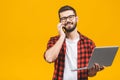 Happy smiling young business man in casual with a laptop sitting at floor calling with smart phone Royalty Free Stock Photo