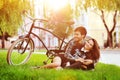 Happy smiling young couple lying in a park near a vintage bike Royalty Free Stock Photo