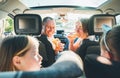 Happy smiling young couple with two daughters eating just cooked Italian pizza sitting in modern car. Happy family moments,