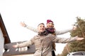 Happy smiling young couple in upper garments with arms outstretched standing having fun together in yard near house. Royalty Free Stock Photo