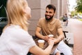 Happy smiling young dating couple having coffee together and enjoying life sitting at table holding hands in street cafe Royalty Free Stock Photo