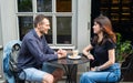 Happy smiling young dating couple having coffee together and enjoying life sitting at table in street cafe on summer day Royalty Free Stock Photo