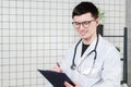 Happy smiling young doctor writing on clipboard in a modern hospital Royalty Free Stock Photo