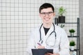 Happy smiling young doctor writing on clipboard in a modern hospital Royalty Free Stock Photo