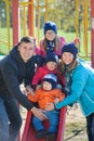 Happy smiling young family of five at children`s playground in park Royalty Free Stock Photo