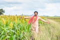 Happy smiling young farmer walking at corn field by feeling nature at framland - concept of happiness, freedom and