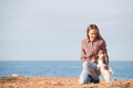Happy smiling young caucasian female in plaid shirt and jeans with her small pet chihuahua dog on sea coast Royalty Free Stock Photo