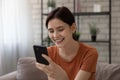 Young female sit on sofa hold phone read love message Royalty Free Stock Photo