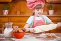 Happy smiling young girl chef in kitchen making dough Royalty Free Stock Photo