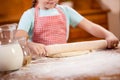 Happy smiling young girl chef in kitchen making dough Royalty Free Stock Photo