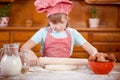 Happy smiling young girl chef in kitchen making dough Royalty Free Stock Photo