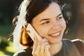 Happy, smiling young girl talking on a mobile phone in a city park. Young beautiful lady talking on her smartphone outdoors. An Royalty Free Stock Photo