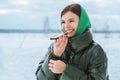 A happy smiling young girl talking on a mobile phone in a snowy winter park. A beautiful laughing girl with a mobile phone in a wi Royalty Free Stock Photo