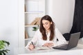 Happy smiling young girl working in the office. The girl writes in a notebook. Close-up portrait of an office worker. Positive you Royalty Free Stock Photo