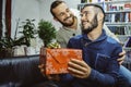 Happy smiling young handsome gay couple in love looking at each other celebrating and giving gift Royalty Free Stock Photo