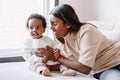 Happy smiling young Indian mother playing with black baby girl daughter. Family mixed race people mom and a kid together hugging