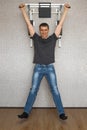 Happy smiling young man doing pull-up exercises on horizontal bar at his home Royalty Free Stock Photo