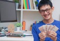 Happy smiling a young man holding money fans in hands. Cheerful gambler getting big cash prize at online working Royalty Free Stock Photo