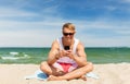 Happy smiling young man with smartphone on beach Royalty Free Stock Photo