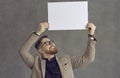 Studio portrait of a happy young businessman holding a blank paper mockup banner Royalty Free Stock Photo