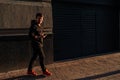 Happy smiling young man using modern smart phone while standing at crosswalk at the sunset in city center Royalty Free Stock Photo