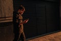 Happy smiling young man using modern smart phone while standing at crosswalk at the sunset in city center Royalty Free Stock Photo